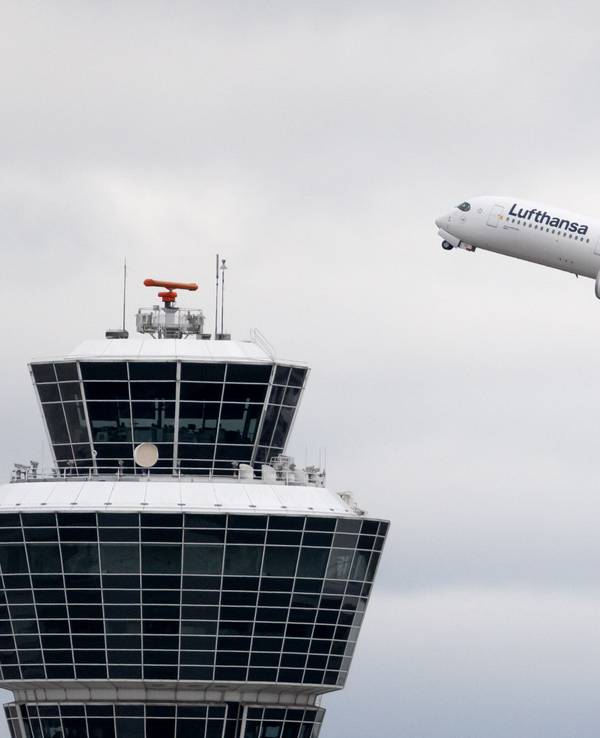 Ein Flugzeug der Lufthansa startet am Flughafen München und fliegt am Tower vorbei.