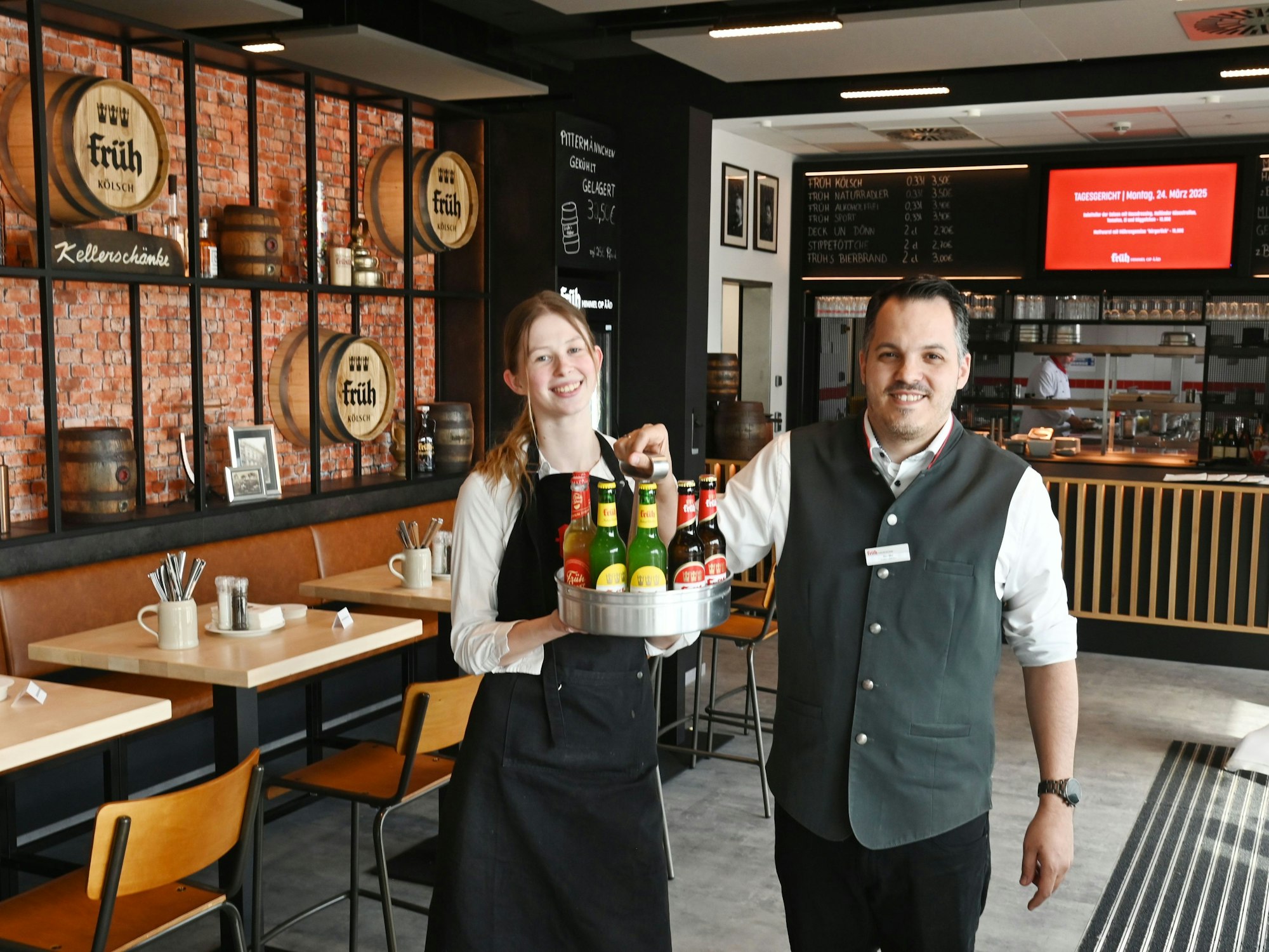 Ein Mann und eine Frau halten ein Tablet mit Getränken.
