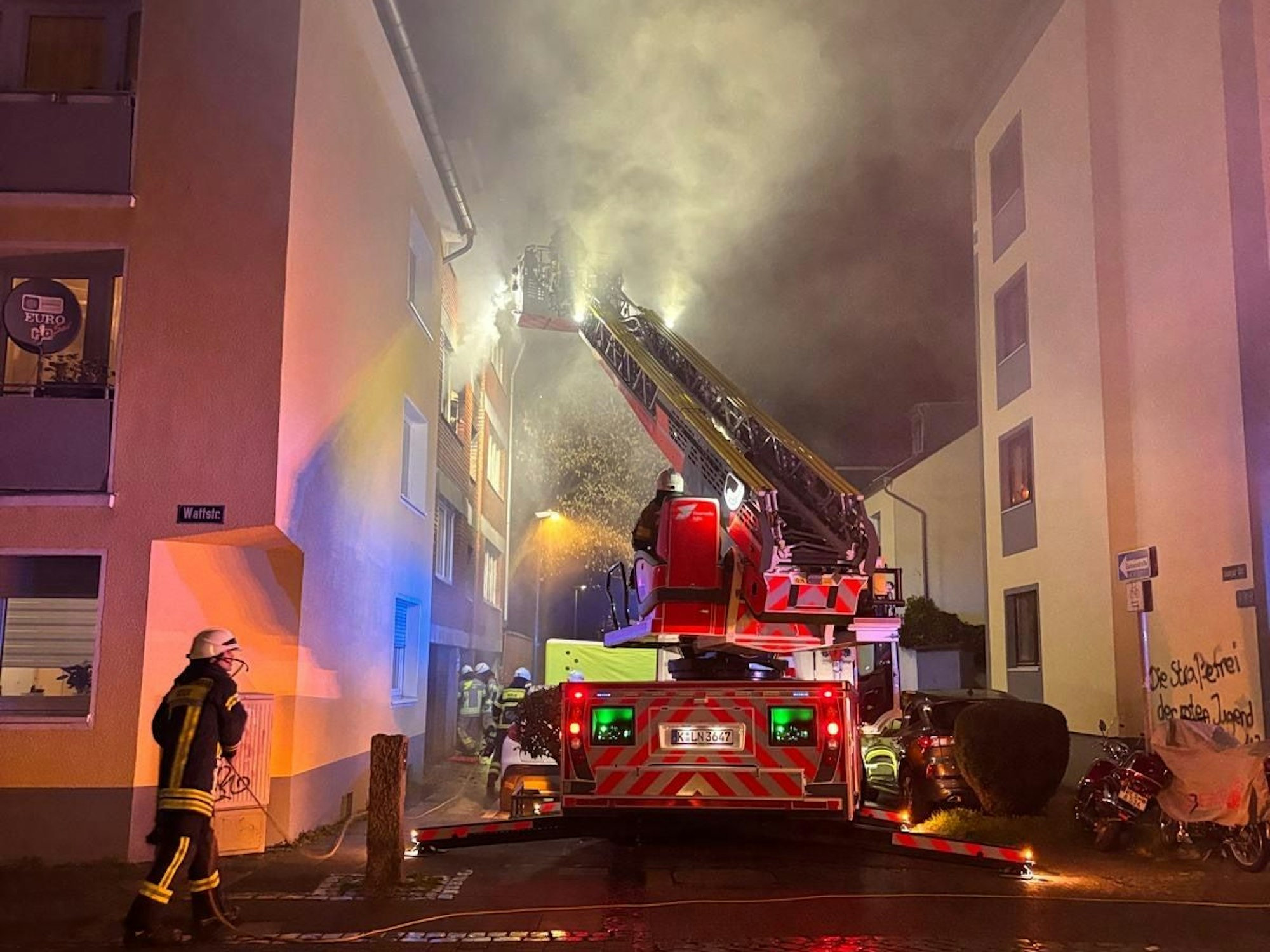 Aus einem Fenster dringt starker Qualm, die Drehleiter der Feuerwehr ist ausgefahren.