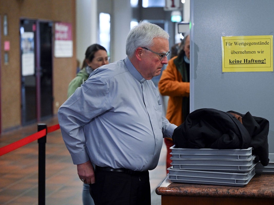 Heiner Koch, Erzbischof von Berlin, legt seine Sachen in eine Schale für die Sicherheitskontrolle.