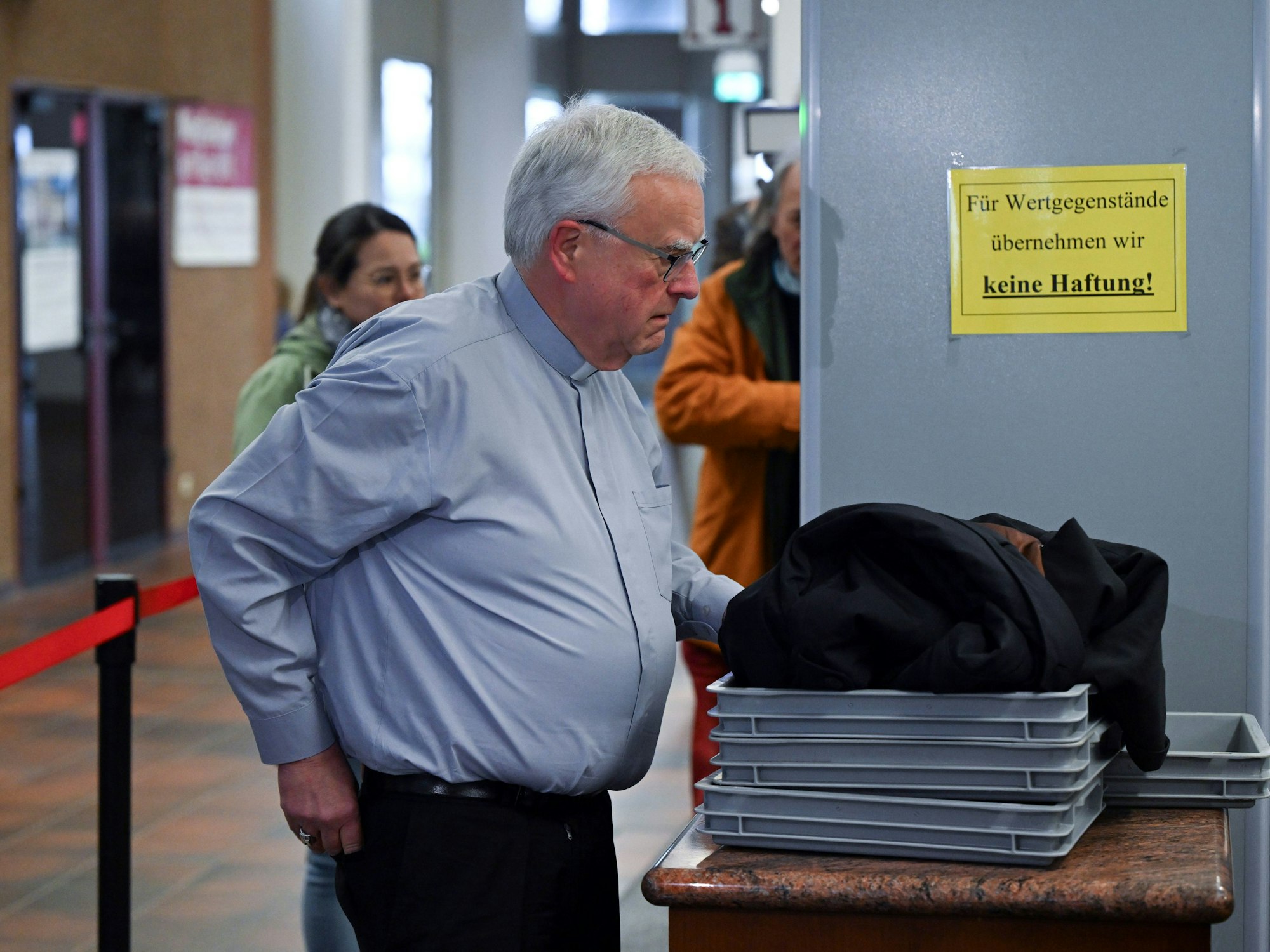 Heiner Koch, Erzbischof von Berlin, legt seine Sachen in eine Schale für die Sicherheitskontrolle.