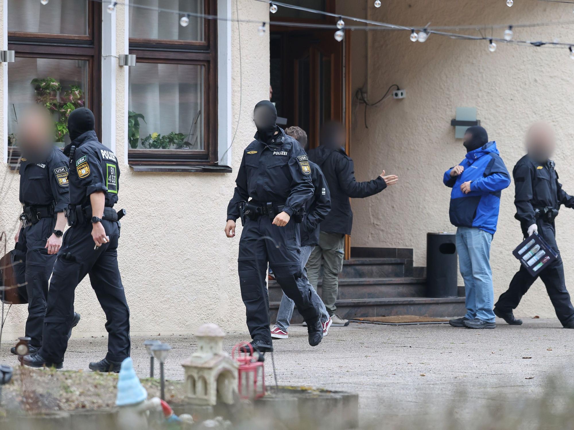Polizeibeamte verlassen ein durchsuchtes Haus.