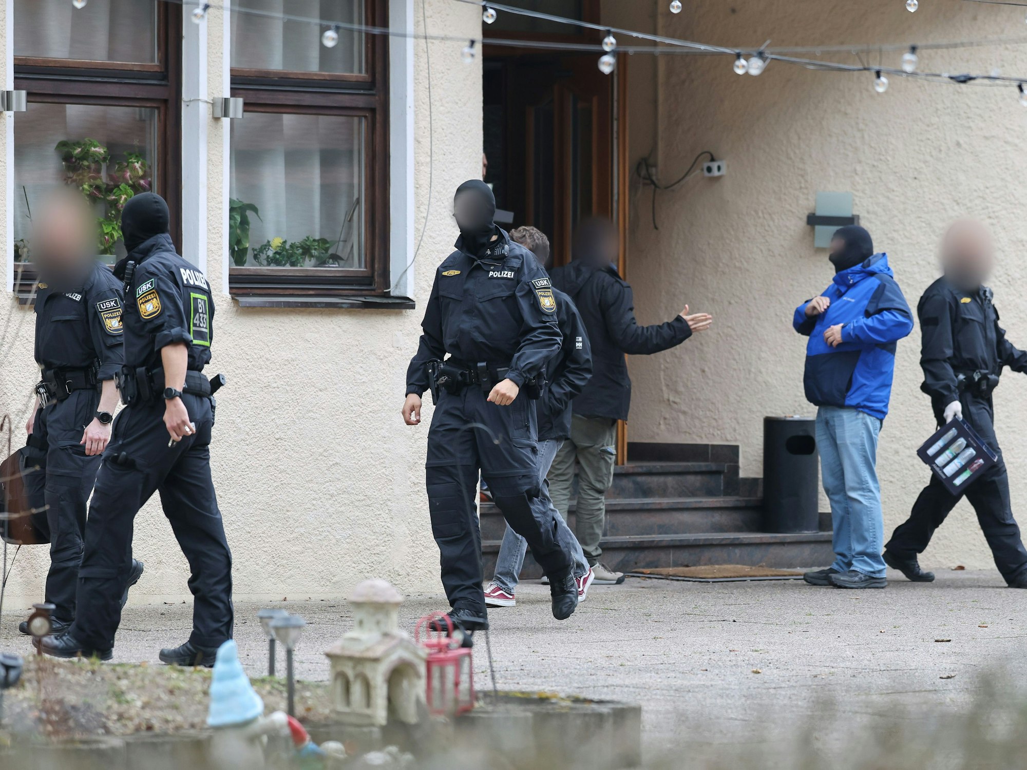 Polizeibeamte verlassen ein durchsuchtes Haus.