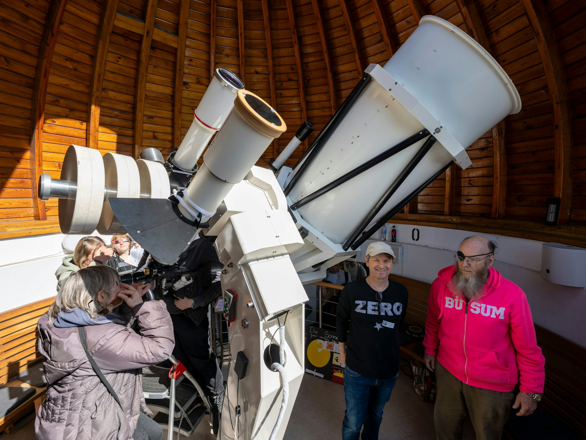 Eine Frau guckt durch ein Riesen-Teleskop.