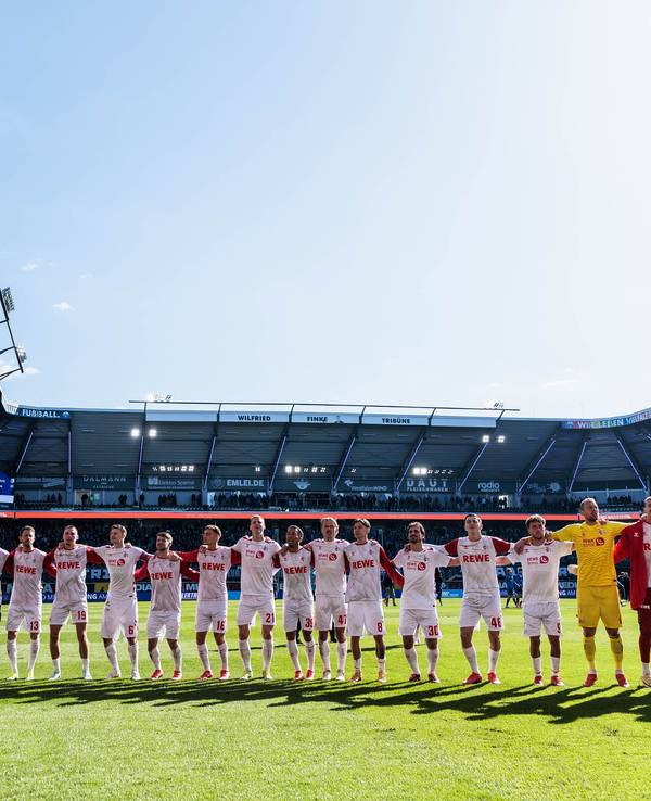 Die Mannschaft des 1. FC Köln feiert den Sieg mit den mitgereisten Fans.