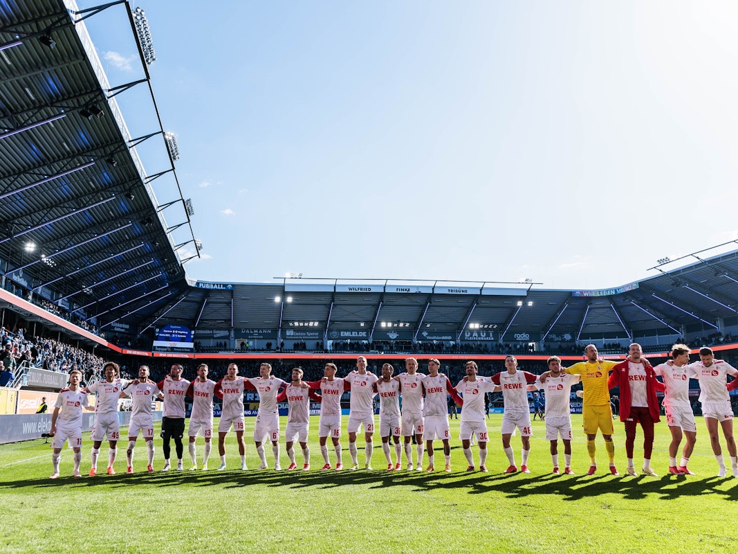Die Mannschaft des 1. FC Köln feiert den Sieg mit den mitgereisten Fans.