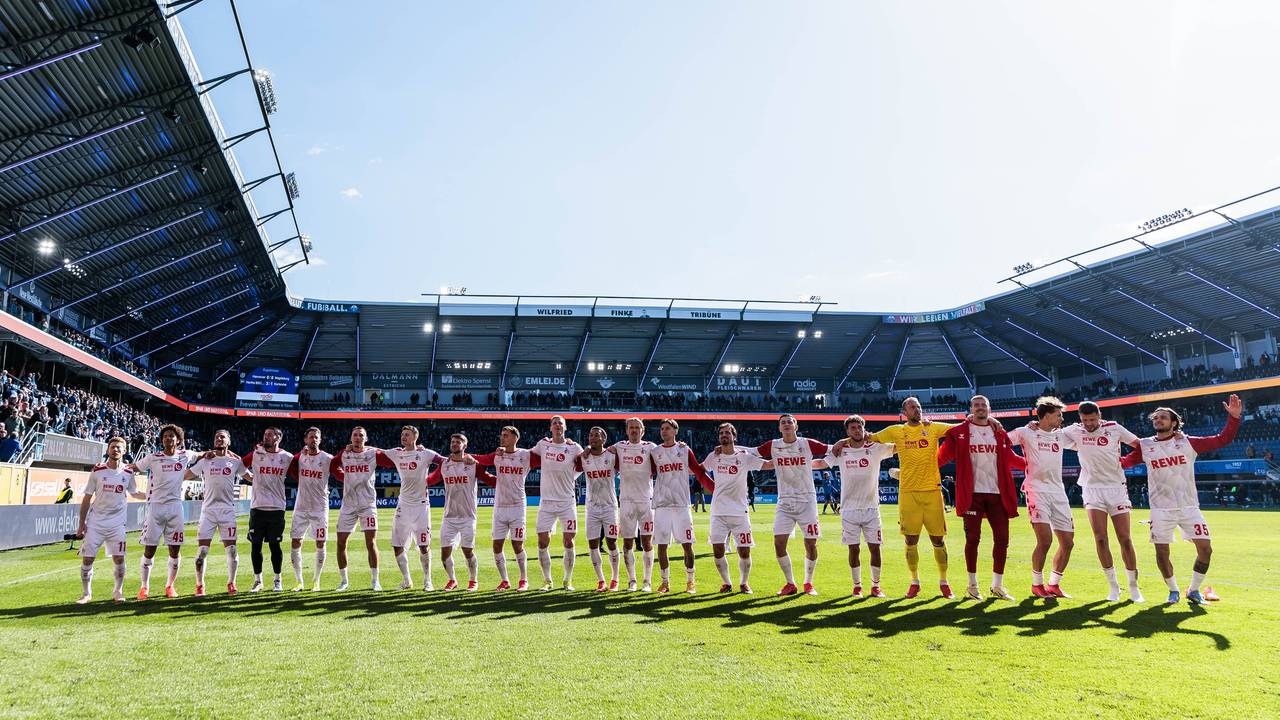 Die Mannschaft des 1. FC Köln feiert den Sieg mit den mitgereisten Fans.