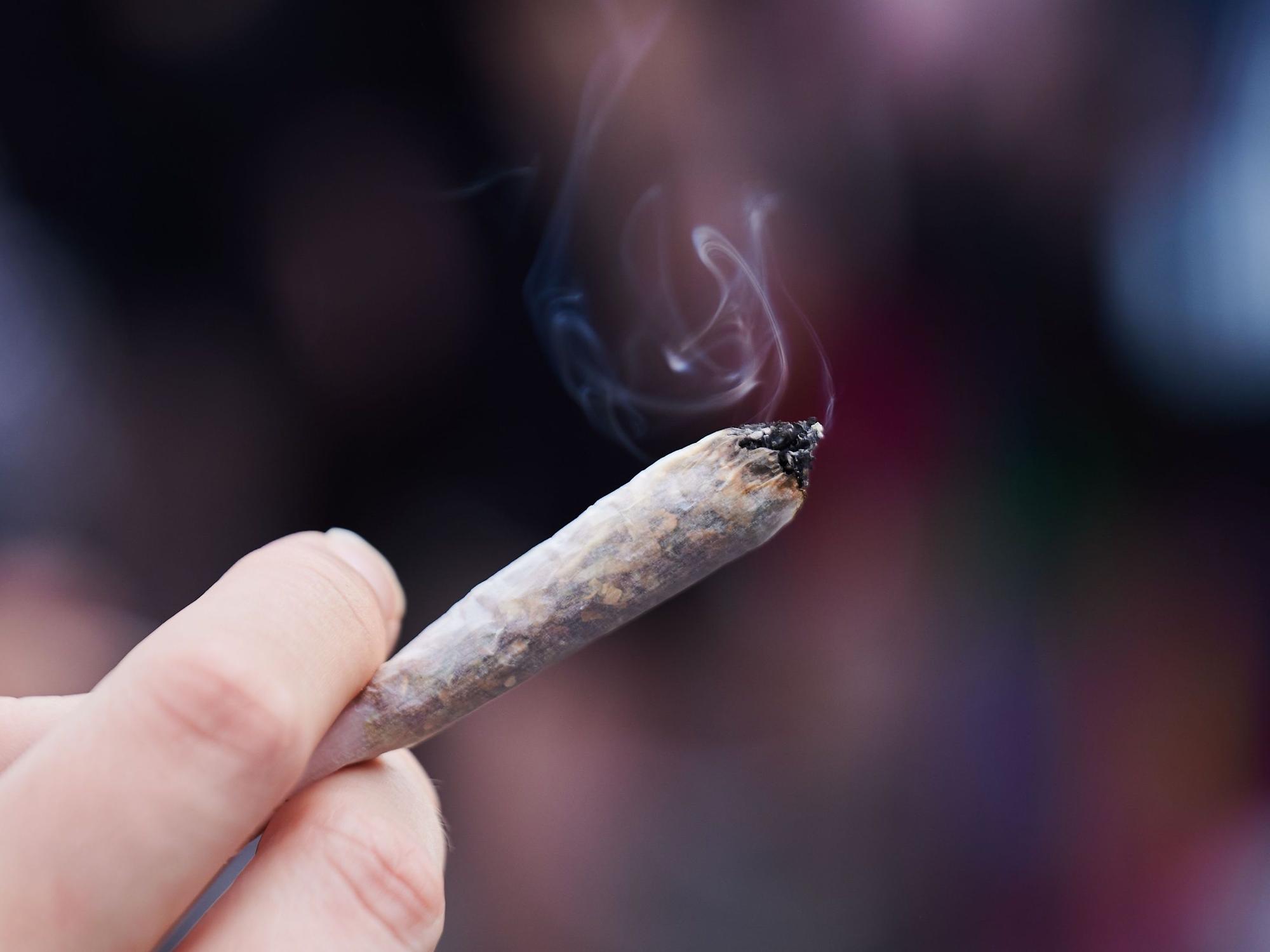 Eine Frau hält einen Joint in der Hand.