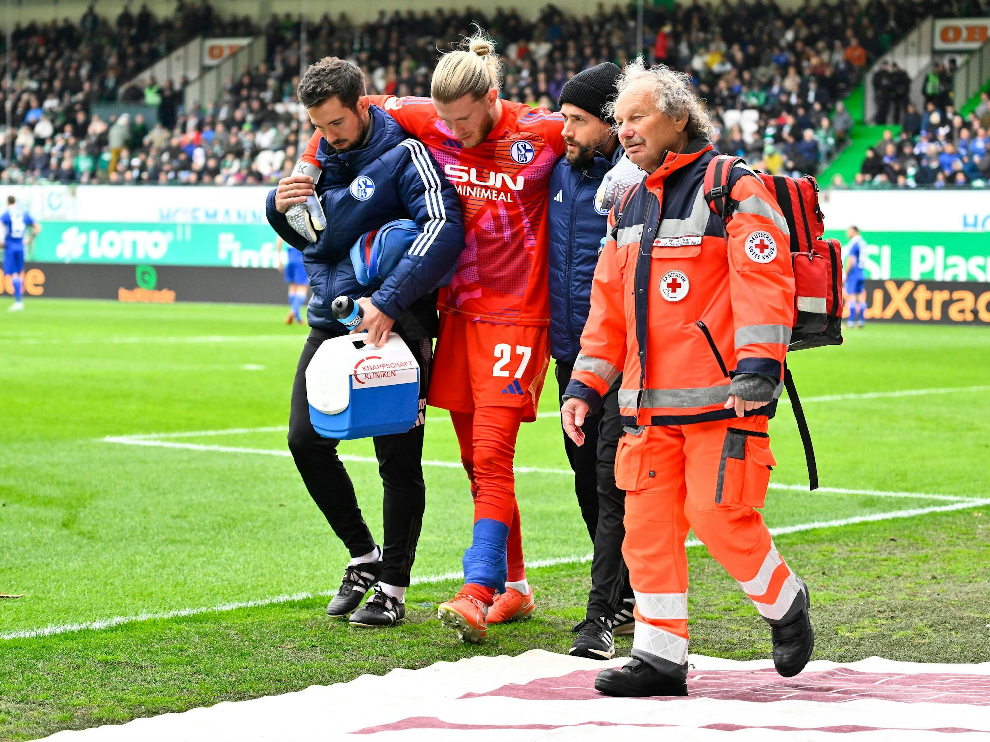 Loris Karius wird von zwei Betreuern gestützt.