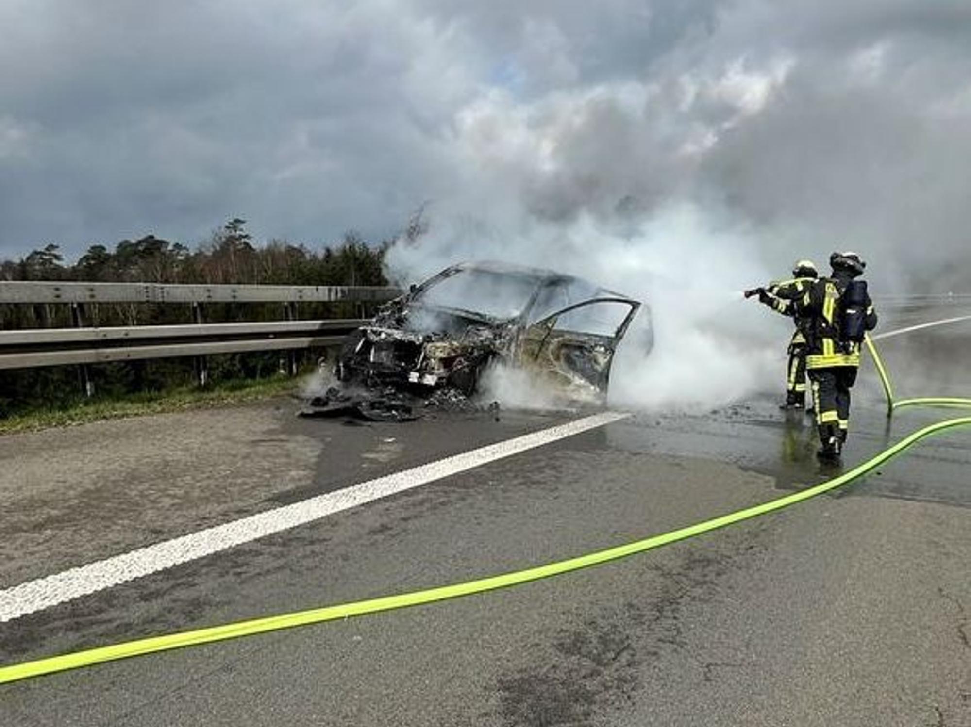 Einsatzkräfte der Feuerwehr löschen am 30. März 2025 das brennende Auto auf der A1 bei Wermelskirchen.