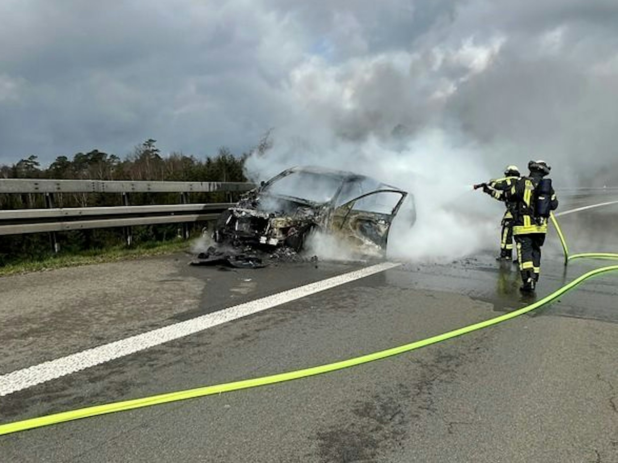 Einsatzkräfte der Feuerwehr löschen am 30. März 2025 das brennende Auto auf der A1 bei Wermelskirchen.