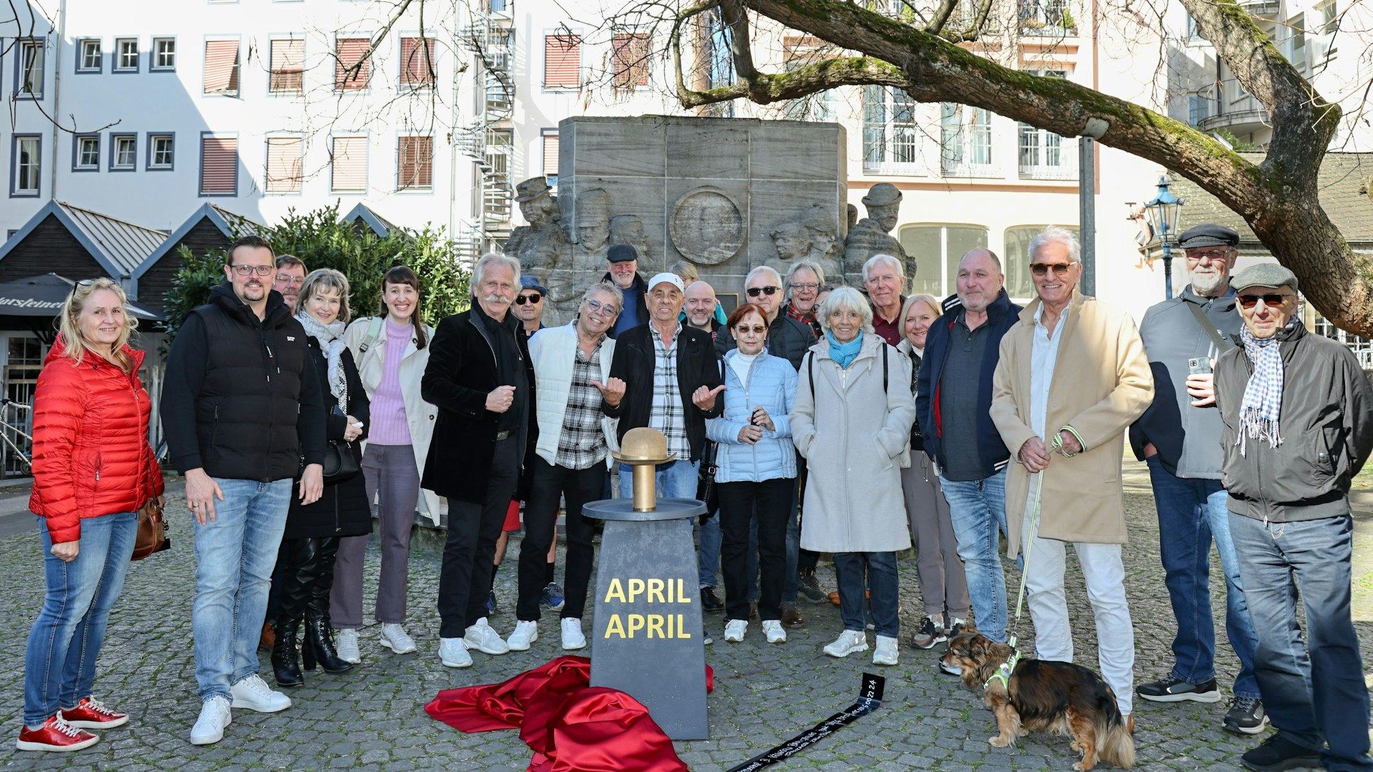 Passanten stehen mit den Musikern am Ostermann-„Denkmal“.