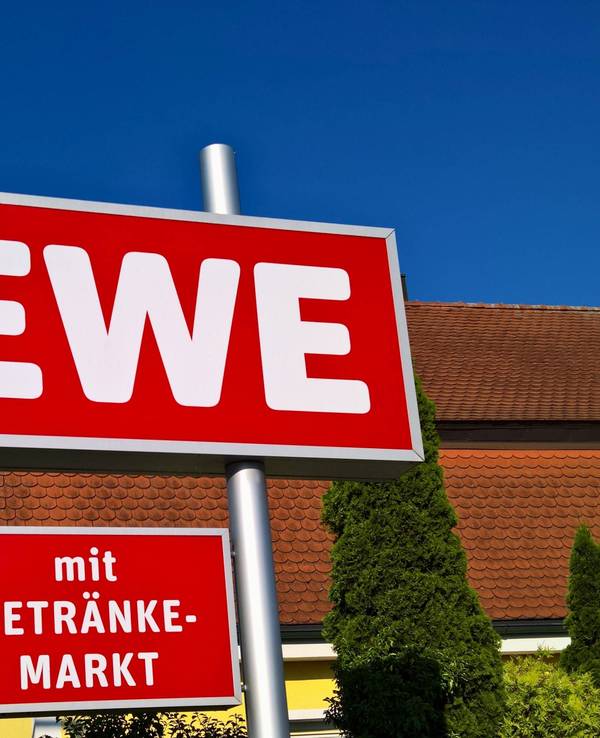 Ein Rewe-Schild vor einem Markt.
