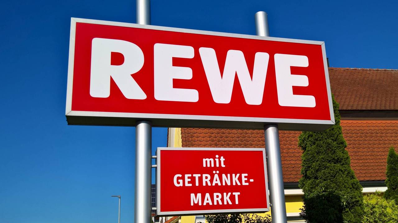Ein Rewe-Schild vor einem Markt.