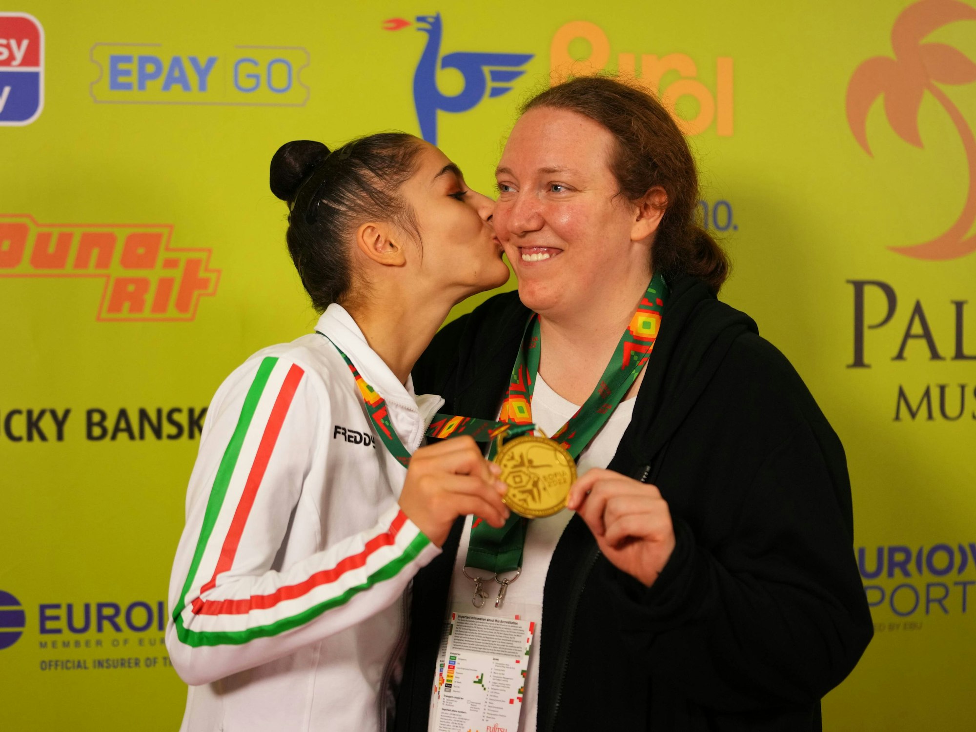 Julieta Cantaluppi hält mit Turnerin Sofia Raffaeli, die sie auf die Wange küsste, die Goldmedaille in die Kamera.
