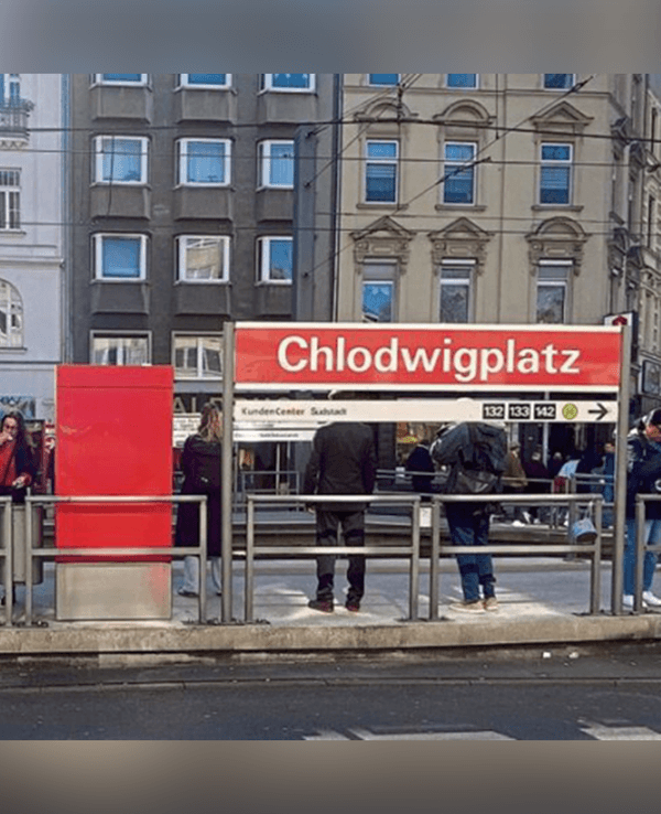 Menschen stehen an einer Haltestelle.