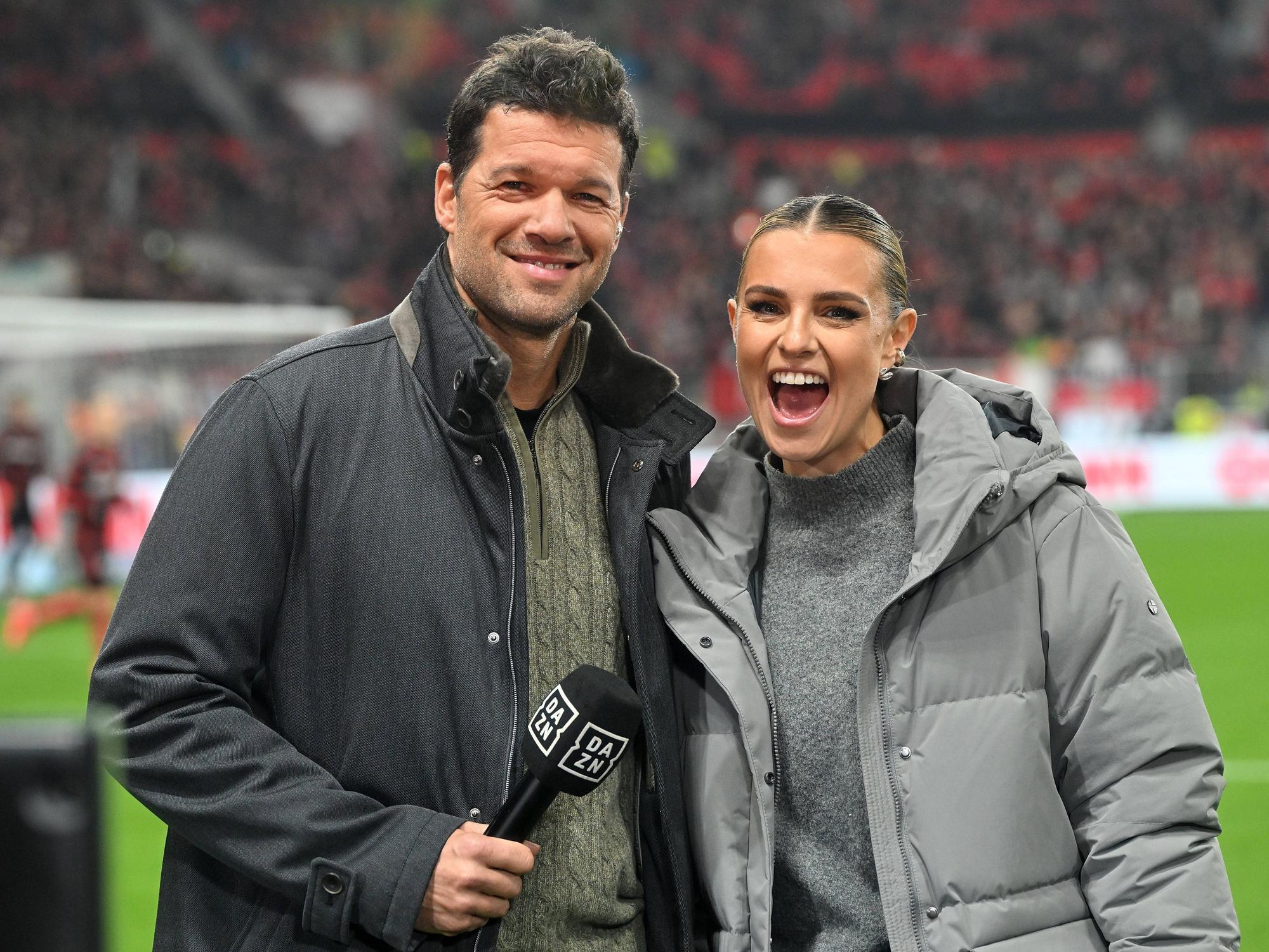 DAZN-Experte Michael Ballack steht neben DAZN-Moderatorin Laura Wontorra auf dem rasen.