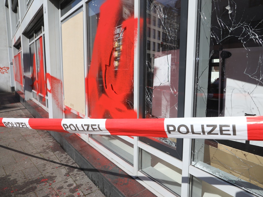 Drei Scheiben einer Fensterfront sind eingeworfen, ein Fenster sowie die Fassade mit roter Farbe besprüht worden.