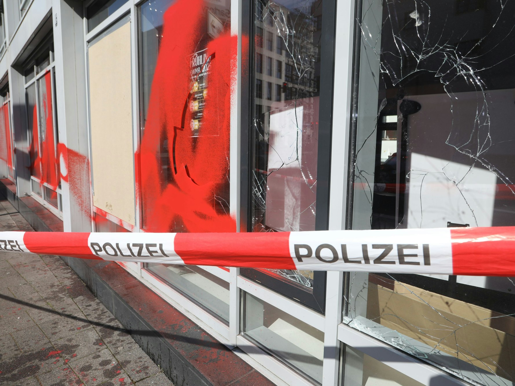 Drei Scheiben einer Fensterfront sind eingeworfen, ein Fenster sowie die Fassade mit roter Farbe besprüht worden.