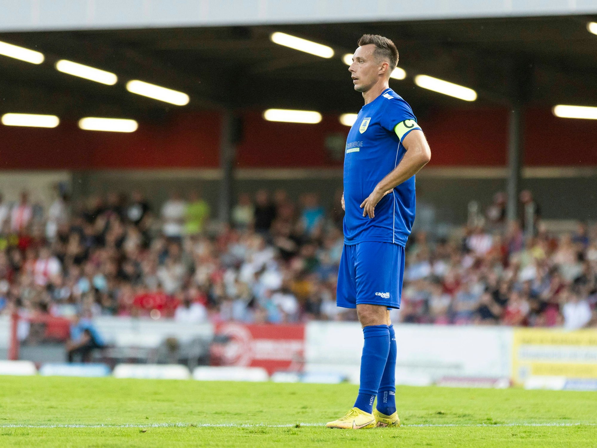 Adam Matuschyk hat die Hände in den Hüften und schaut in die Ferne.