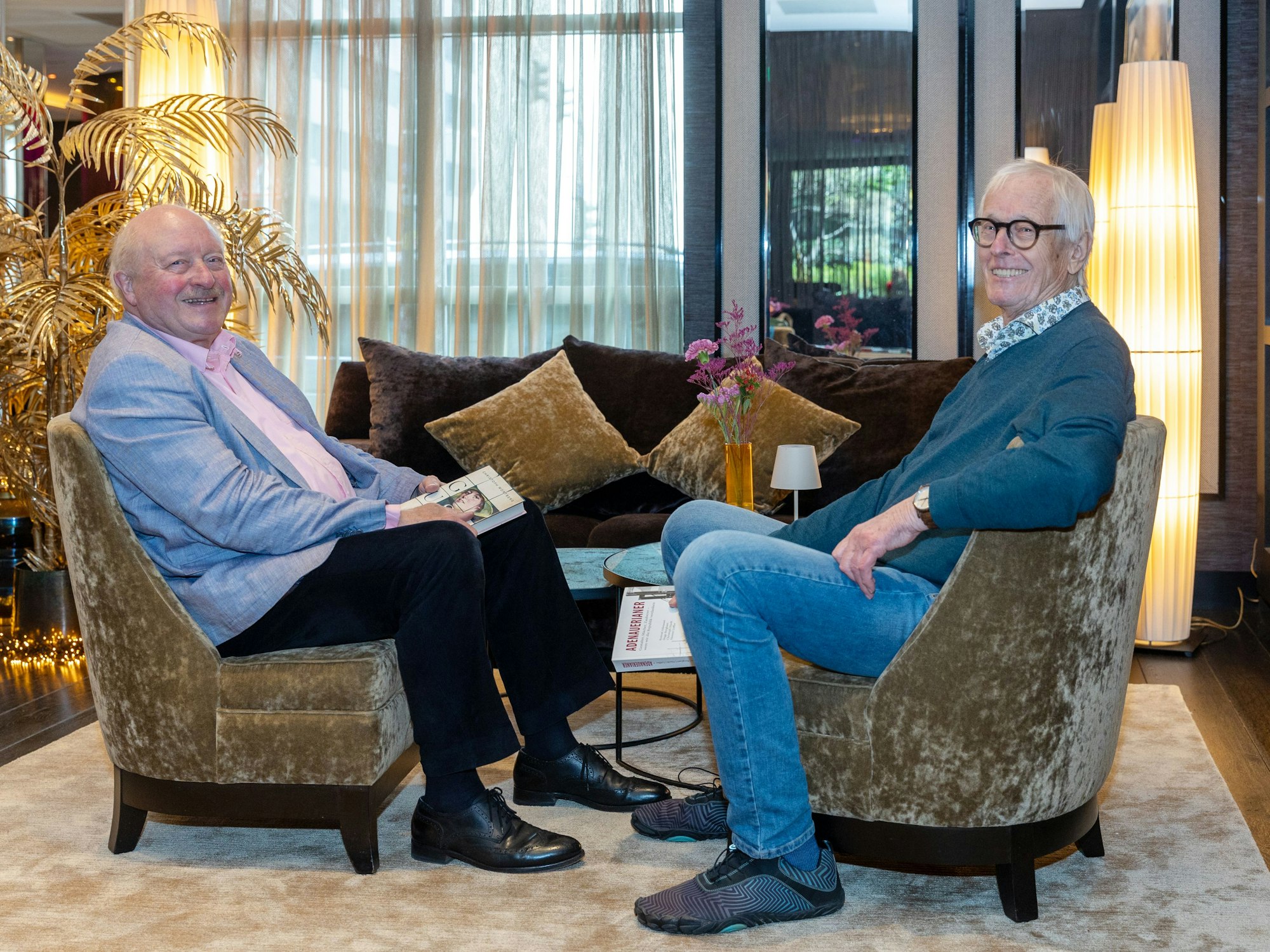 Zwei Männer sitzen an einem Tisch in einer Hotellobby.