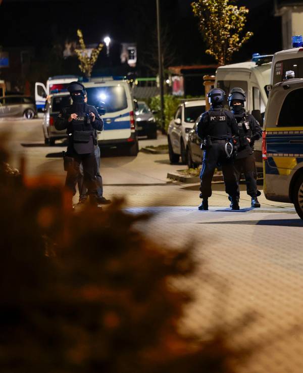 Einsatzkräfte der Polizei stehen neben geparkten Polizeifahrzeugen.
