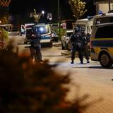 Einsatzkräfte der Polizei stehen neben geparkten Polizeifahrzeugen.