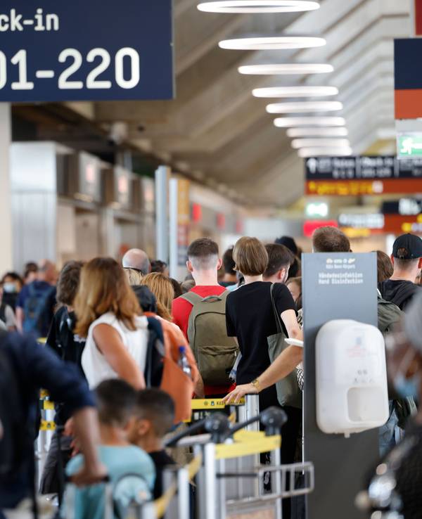 Zahlreiche Passagiere stehen innerhalb und außerhalb der Terminals an, um durch die Sicherheitskontrolle zu gelangen.