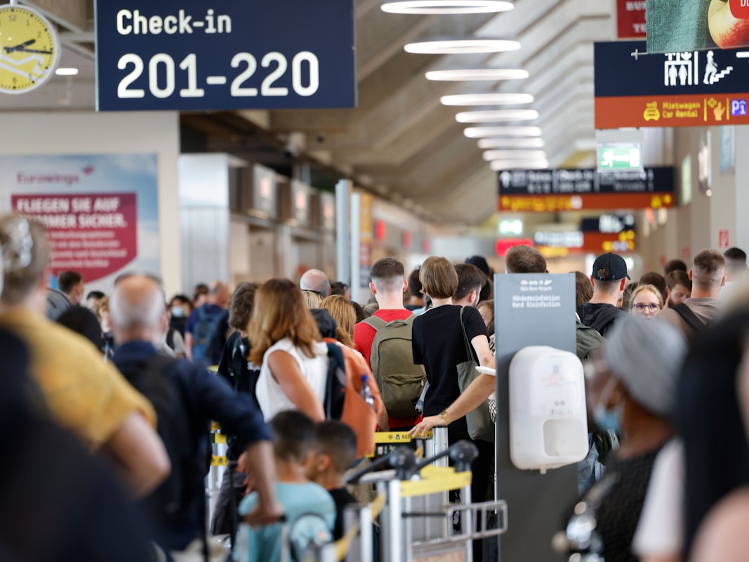 Zahlreiche Passagiere stehen innerhalb und außerhalb der Terminals an, um durch die Sicherheitskontrolle zu gelangen.