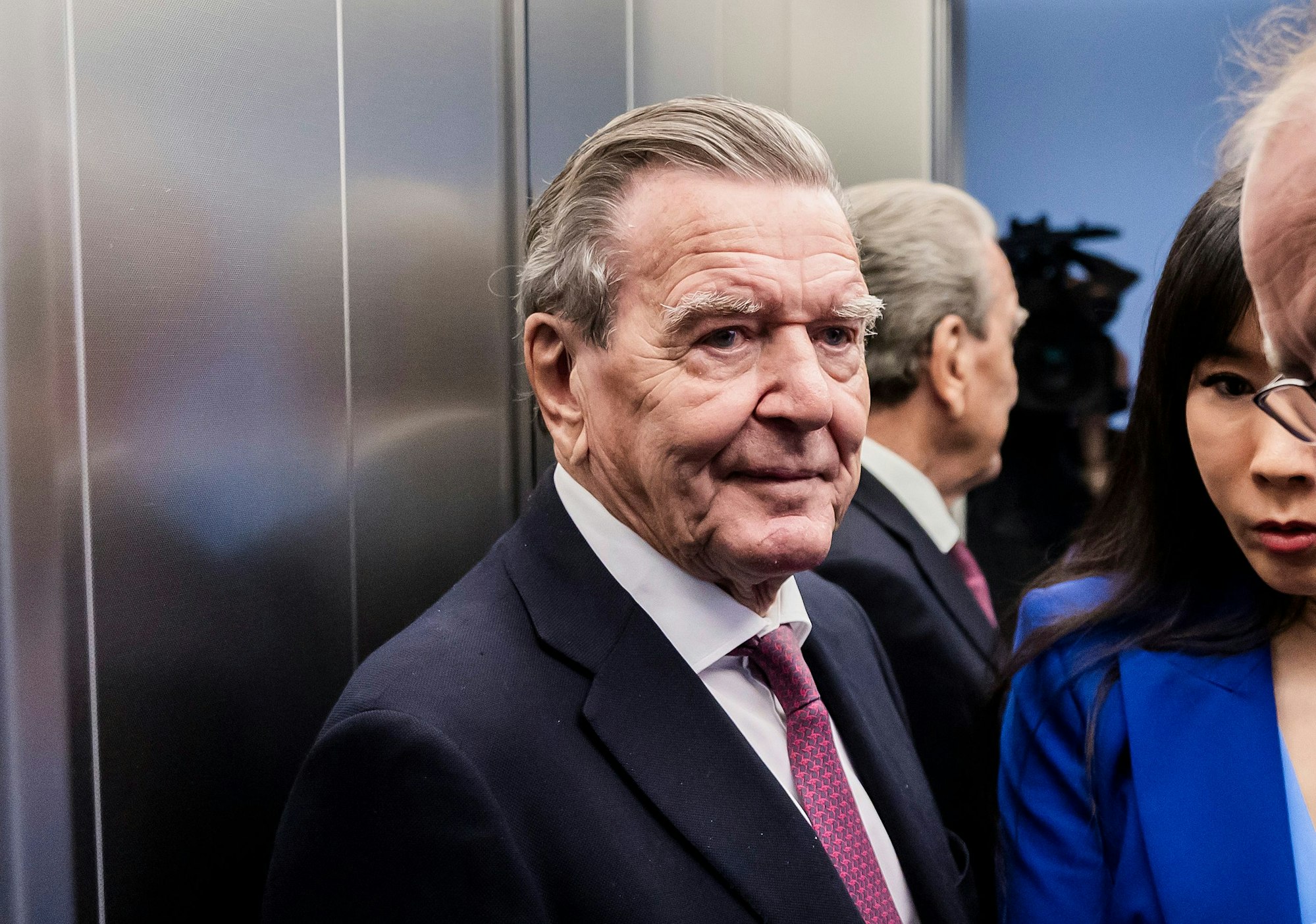 Altkanzler Gerhard Schröder (SPD, l), und seine Ehefrau Soyeon Schröder-Kim (M) stehen im Oberverwaltungsgericht (OVG) Berlin-Brandenburg nach der mündlichen Verhandlung im Prozess um den Verlust seines Büros im Bundestag in einem Aufzug.