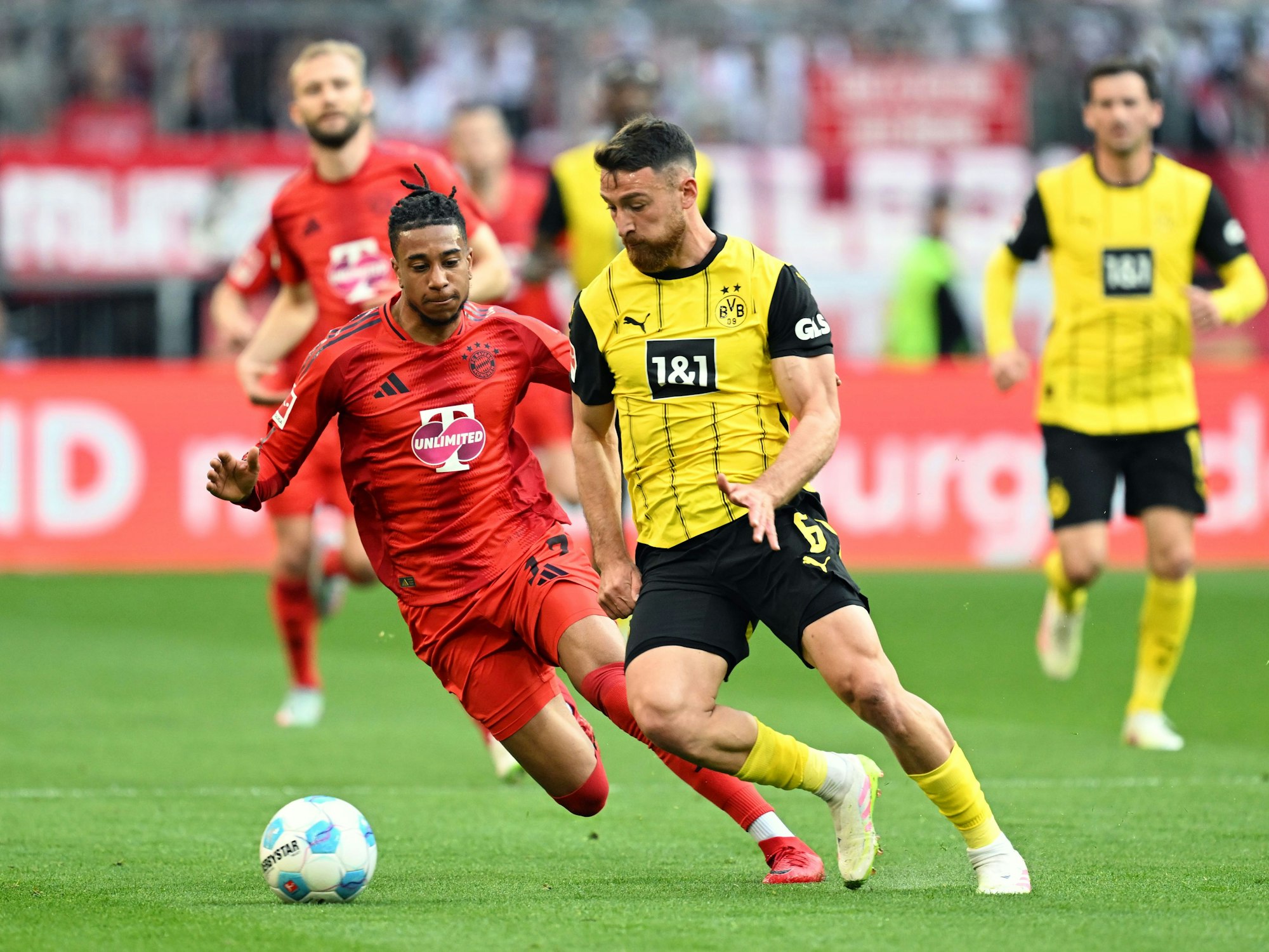 Münchens Michael Olise (l.) und Dortmunds Salih Özcan kämpfen um den Ball.