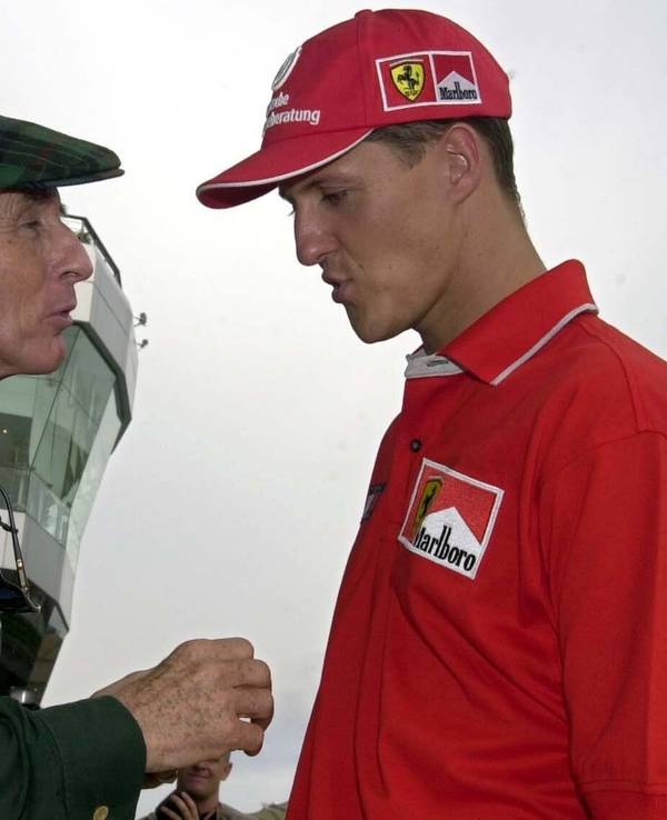 Jackie Stewart (l.) und Michael Schumacher unterhalten sich am Rande der Rennstrecke von Sepang bei Kula Lumpur scherzhaft über die Frage, wer mehr erreicht hat.