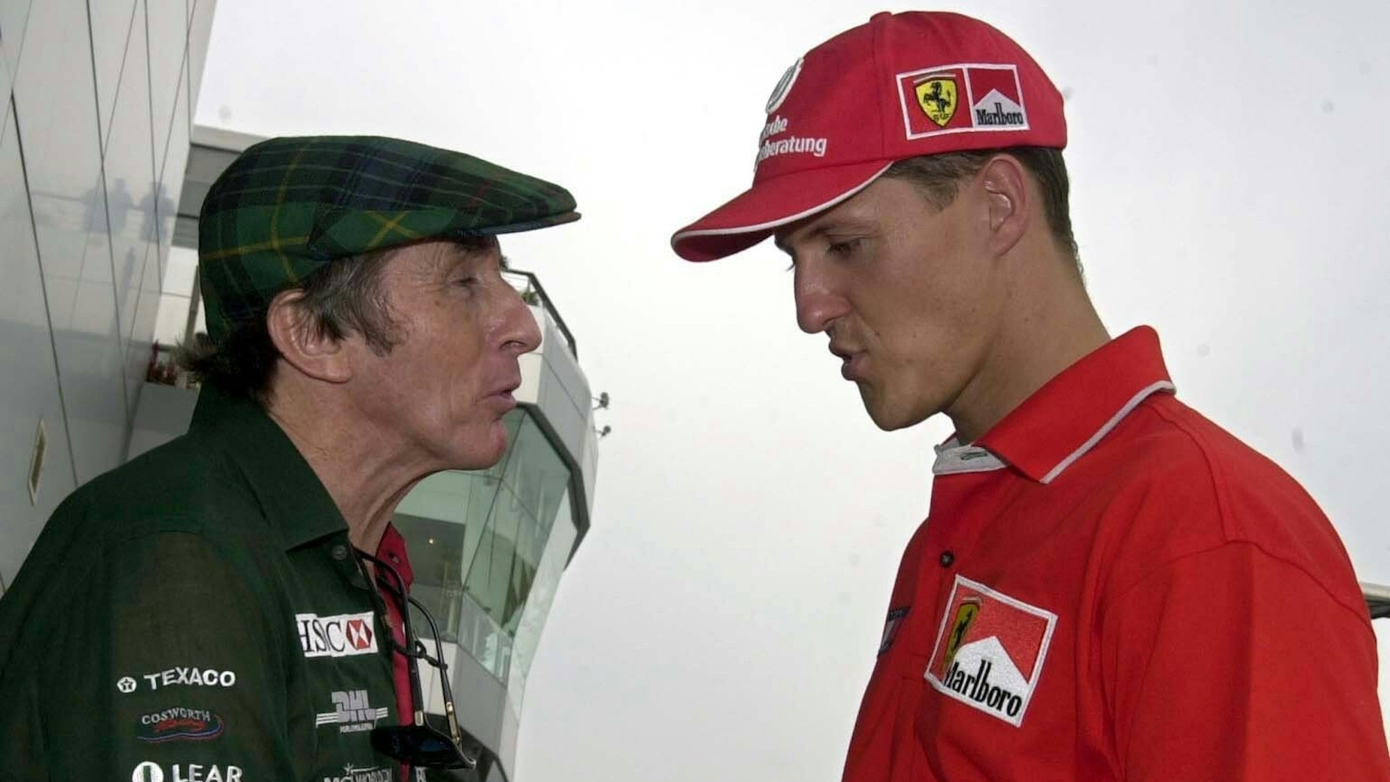 Jackie Stewart (l.) und Michael Schumacher unterhalten sich am Rande der Rennstrecke von Sepang bei Kula Lumpur scherzhaft über die Frage, wer mehr erreicht hat.