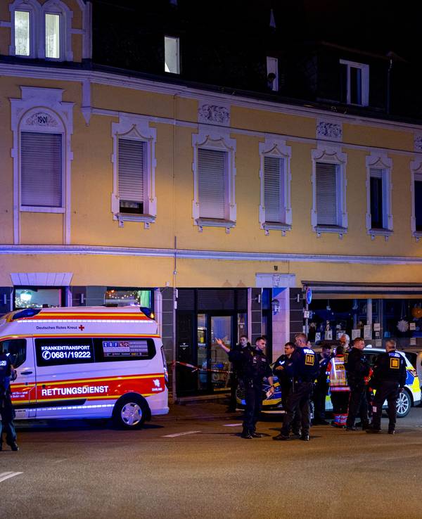 Rettungskräfte und Polizisten stehen am 11. April 2025 auf einer Straße im Saarbrücker Bezirk Dudweiler. Bei einer Auseinandersetzung mit fünf Beteiligten in Saarbrücken sind vier Menschen mit einem Messer verletzt worden.