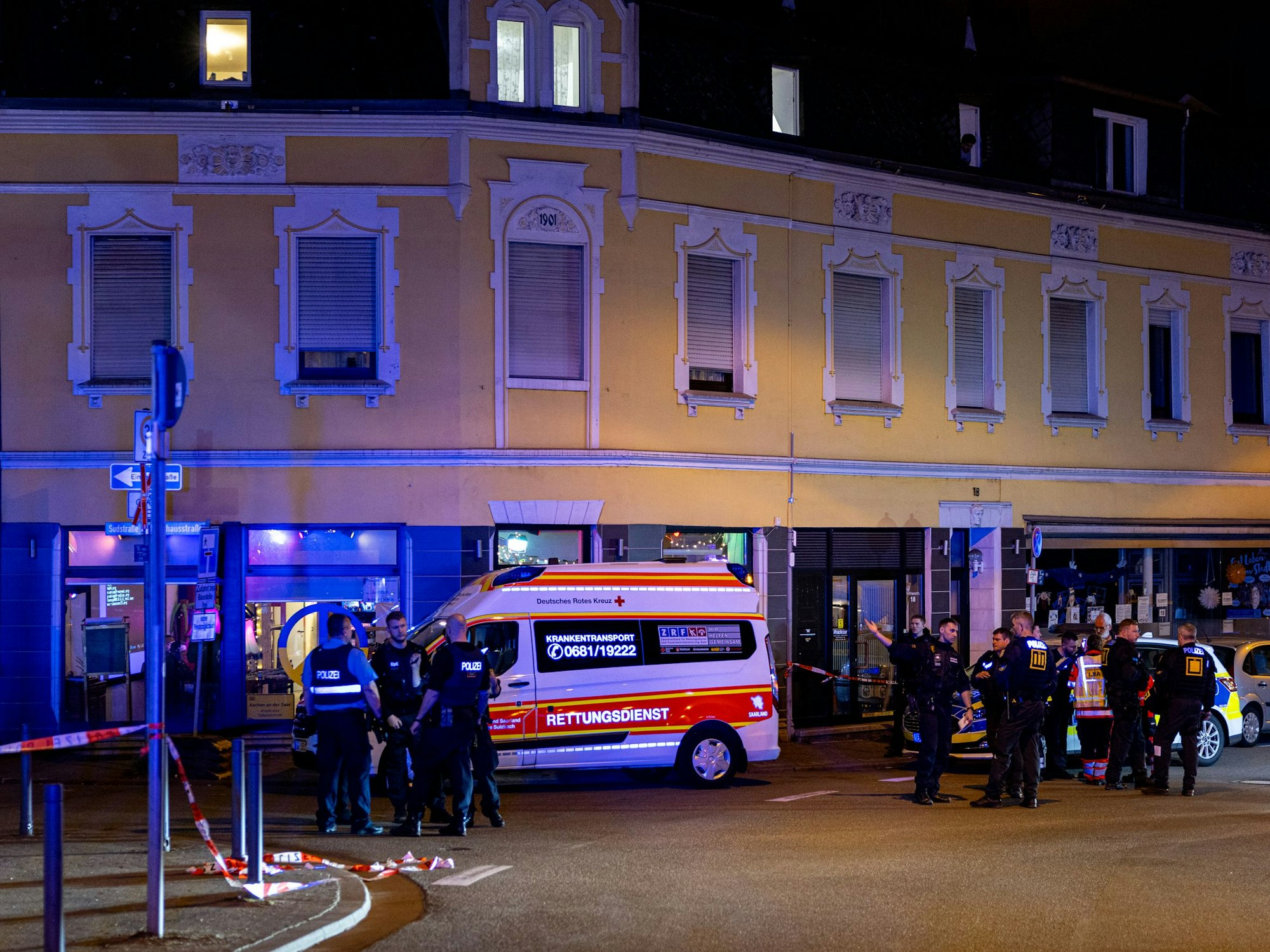 Rettungskräfte und Polizisten stehen am 11. April 2025 auf einer Straße im Saarbrücker Bezirk Dudweiler. Bei einer Auseinandersetzung mit fünf Beteiligten in Saarbrücken sind vier Menschen mit einem Messer verletzt worden.