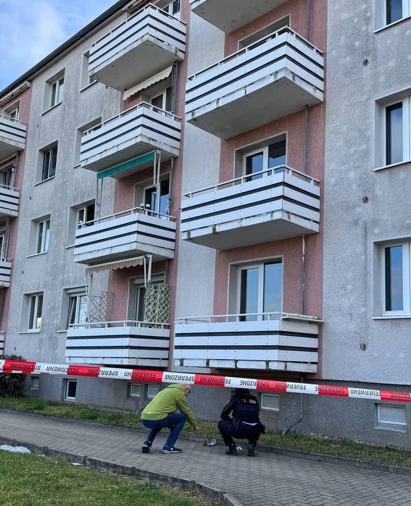 Ermittler der Polizei untersuchen am 12. April 2025 Spuren unter Balkonen an einer Hausfassade. Eine Frau und ein Kind sind beim Sturz von einem Balkon schwer verletzt worden und in ein Krankenhaus gebracht worden.
