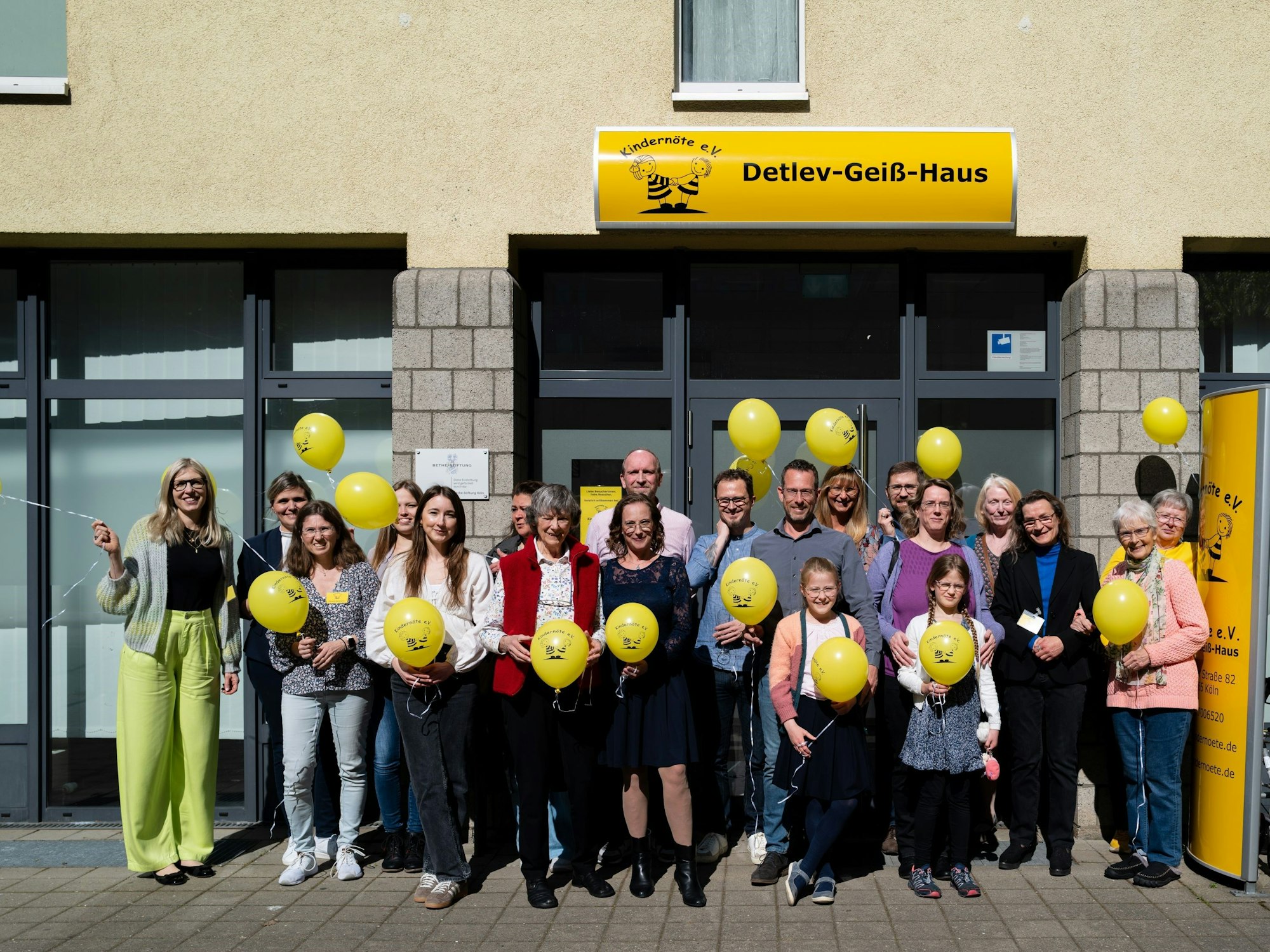 Eine Gruppe Menschen steht vor einem Haus mit Luftballons.