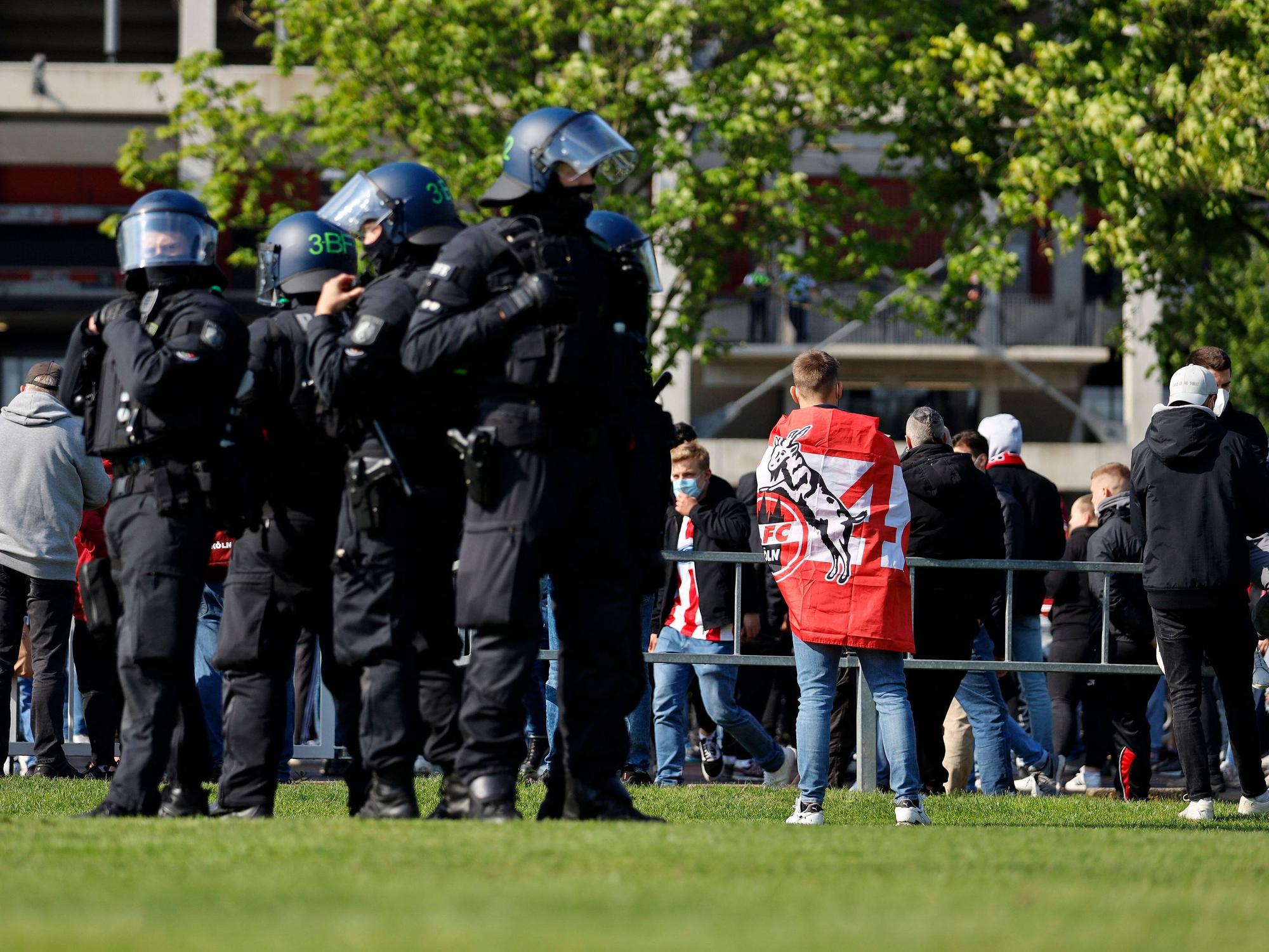 Eine Gruppe von Bundespolizisten steht auf einer Wiese und beobachtet Fans des 1. FC Köln.