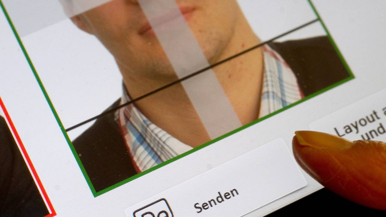 Zu sehen ist ein digital aufgenommenes biometrisches Lichtbild, das auf einem Endgerät zur elektronisch verschlüsselten Übermittlung über eine sichere Verbindung via De-Mail angezeigt wird. Ein Finger zeigt auf das Feld „Senden“ hin.