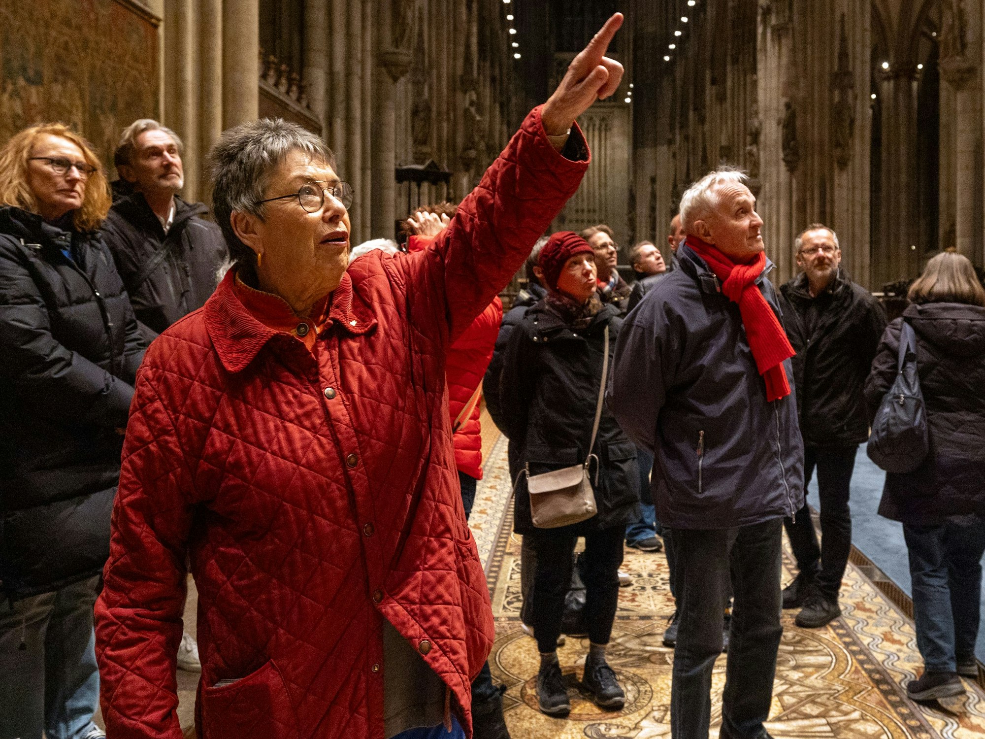 Barbara Schock-Werner steht mit mehreren Menschen im Kölner Dom und zeigt auf etwas.