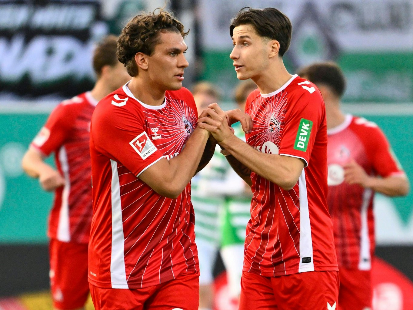 DEVK-Logo auf dem Ärmen von Denis Huseinbasic, der mit Julian Pauli abklatscht.