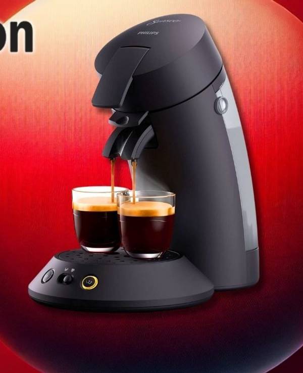 Die Philips Senseo Kaffeemaschine in Schwarz, wie sie gleichzeitig zwei Tassen Kaffee mit cremiger Schaumkrone zubereitet vor einem roten Hintergrund.