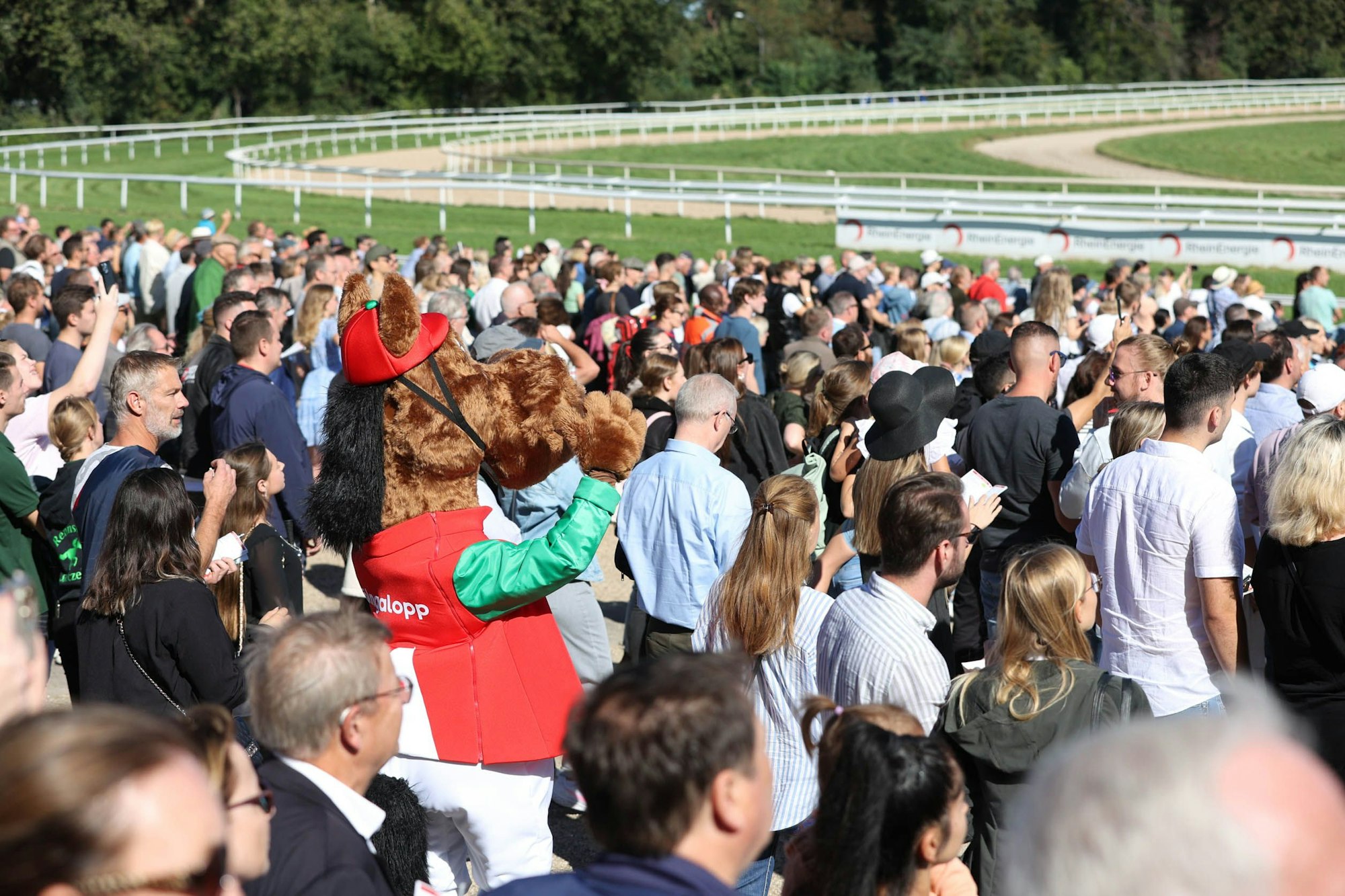Das Maskottchen Galoppi steht in der Zuschauermenge auf der Galopprennbahn in Köln-Weidenpesch.