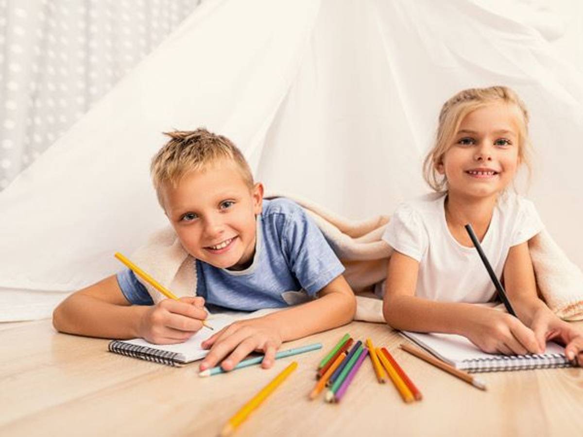 Zwei Kinder liegen auf dem Boden und haben Buntstifte in der Hand.