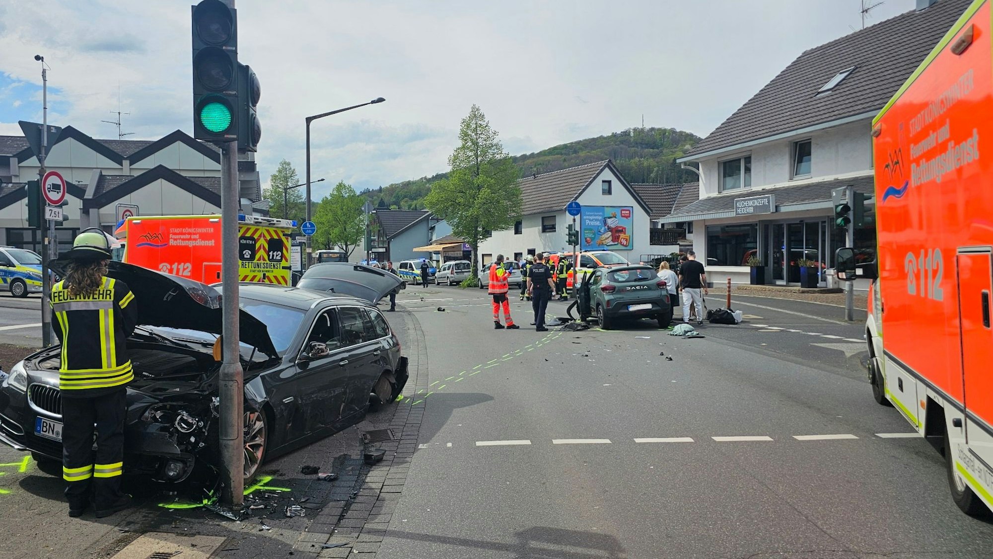 An einer Kreuzung stehen zwei verunglückte Fahrzeuge, auf der Fahrbahn Trümmerteile. Einsatzkräfte von Feuerwehr und Rettungsdienst sind im Einsatz.