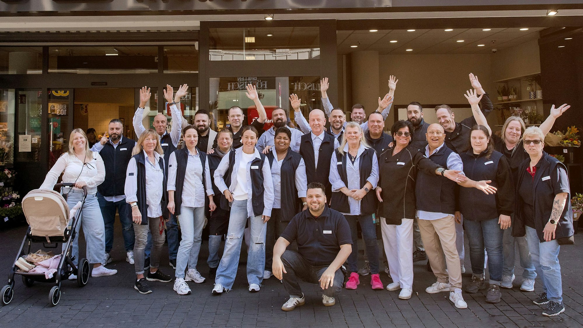 Eine Gruppe von Menschen steht vor einem Supermarkt.