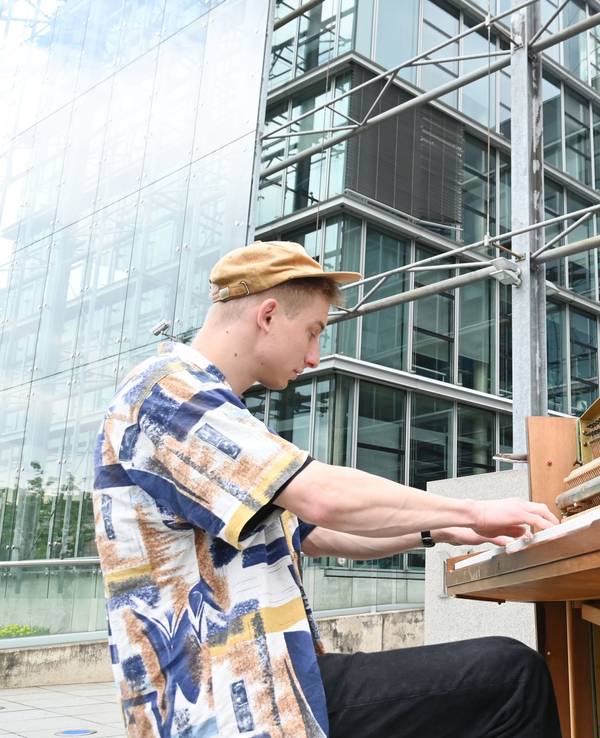 Thelonious Herrmann alias „Stadtgeklimper“ am Piano vor dem Neven DuMont Haus in Köln.