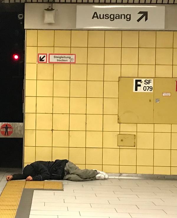 Eine obdachlose Person liegt am Bahnsteig der KVB-Haltestelle Friesenplatz