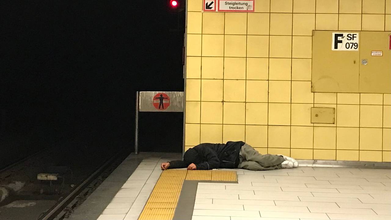 Eine obdachlose Person liegt am Bahnsteig der KVB-Haltestelle Friesenplatz