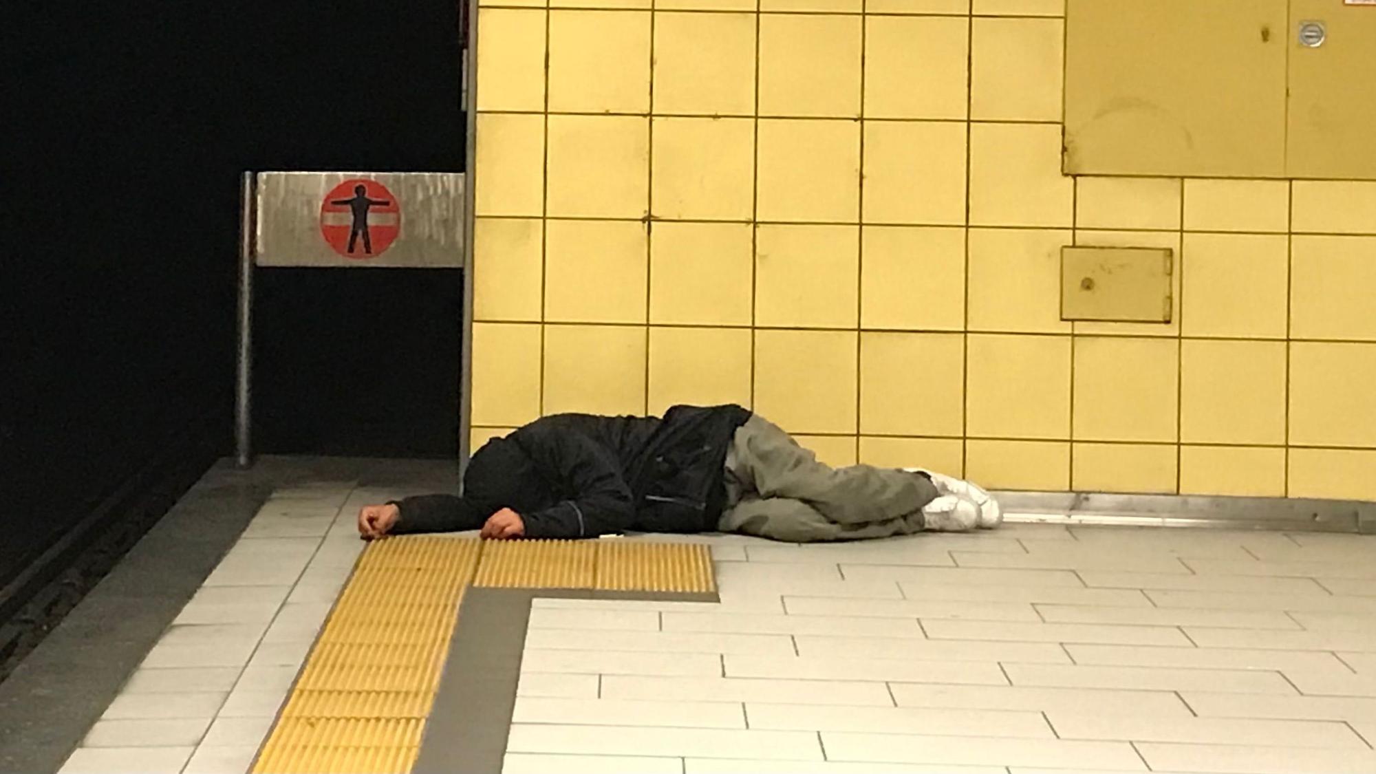 Eine obdachlose Person liegt am Bahnsteig der KVB-Haltestelle Friesenplatz